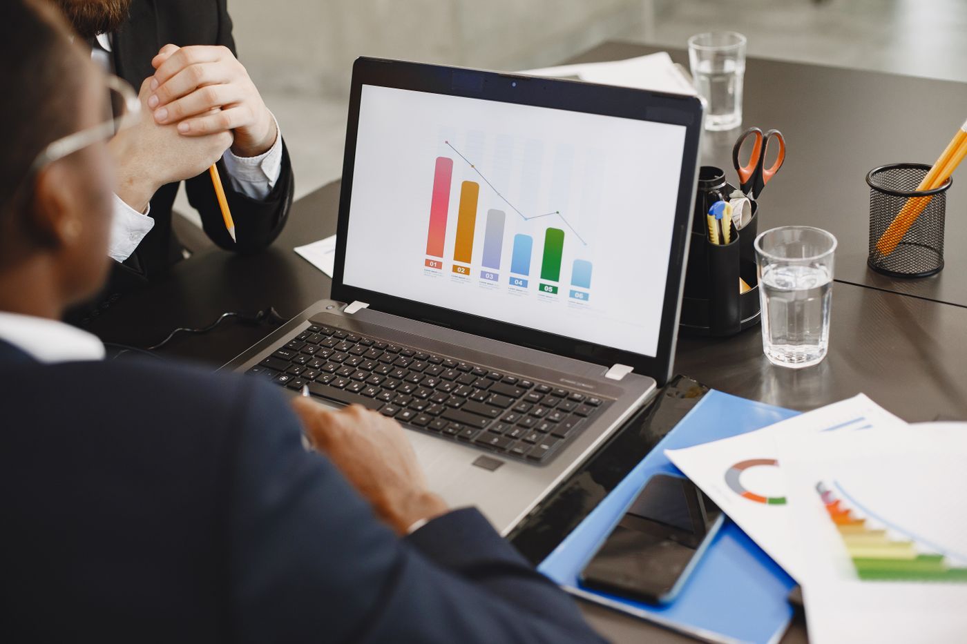 Two managers reviewing a bar chart on a laptop in a meeting